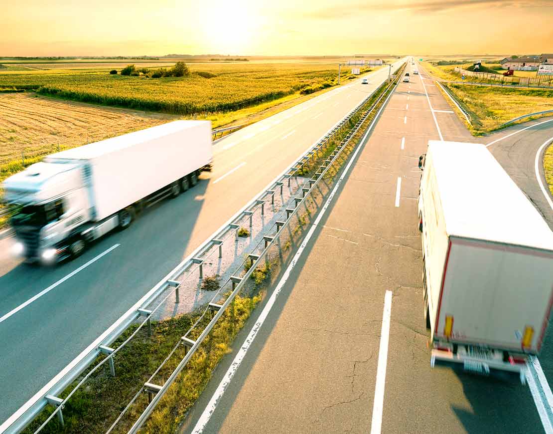 Freight trucks transporting cargo passing each other on highway – ground logistics