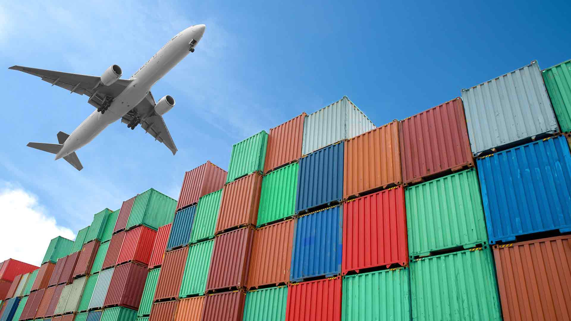 Cargo airplane transporting goods over cargo containers stacked up at port – air logistics